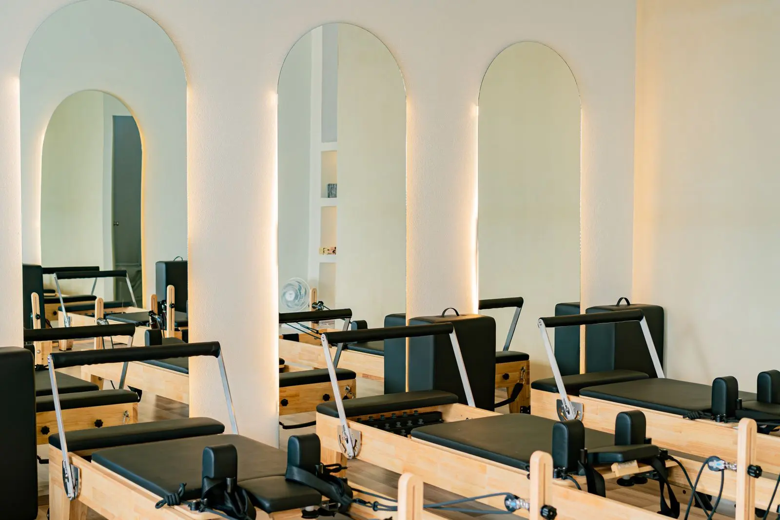 La salle d'exercice de la clinique : miroirs en arche, appareils de bois clair, lumière du matin.